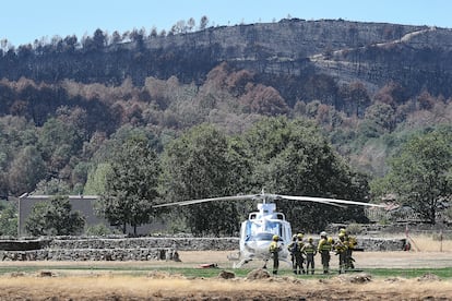 Una cuadrilla de bomberos trabaja en Villardeciervos (Zamora) la pasada semana. Al fondo, parte de la superficie quemada en el incendio de la sierra de la Culebra.