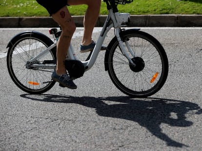 Una hombre transita la madrileña calle Alcalá con una bicicleta del servicio público Bicimad el Día Mundial de la Bicicleta