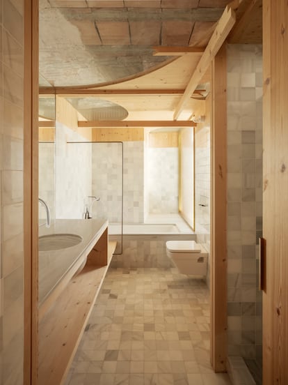 El baño es el único lugar cubierto de azulejos, aunque la madera y el techo desnudo dan continuidad con el resto de la vivienda.