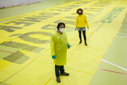 Iván Jaén y Elena Villamor, dos de los voluntarios de Manzanares el Real, confeccionan batas con una pancarta donada por Greenpeace