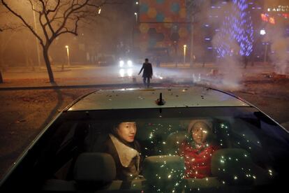 Una niña y una mujer esperan dentro del coche mientras estallan petardos y fuegos artificiales para celebrar el inicio del Año Nuevo en Pekín (China), el 7 de febrero de 2016.