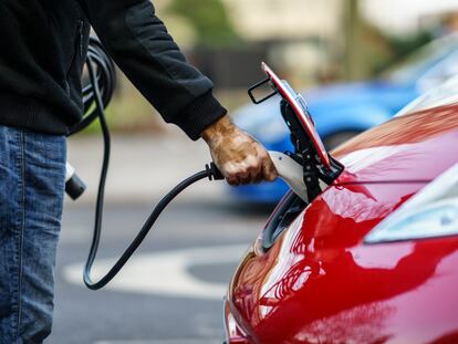 Un conductor carga su coche eléctrico en la calle.