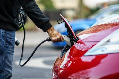 Un conductor carga su coche eléctrico en la calle.