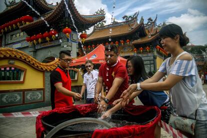 Varios ciudadanos chinos se lavan las manos con agua bendita en el templo Kuan Yin, en Klang (Malasia).