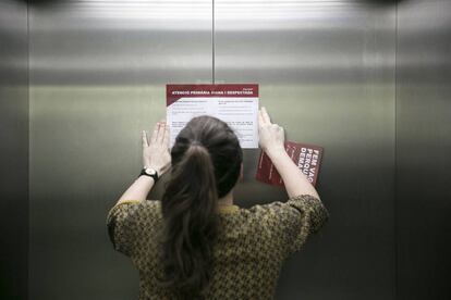 Una treballadora enganxa un cartell sobre la vaga en un dels ascensors del CAP Raval Sud, a Barcelona.