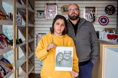 Ao lado do irmão na loja da família, Priscila segura foto do pai e da irmã mortos pela covid-19.