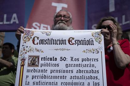 En Sevilla, el ambiente festivo y el calor también han marcado la manifestación, convocada por UGT y CC OO. En la imagen, un hombre sostiene un cartel de la Constitución Española durante la marcha.