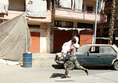 Un combatiente suní traslada a una mujer durante los combates en el barrio de Bab Tebaneh, en Trípoli.