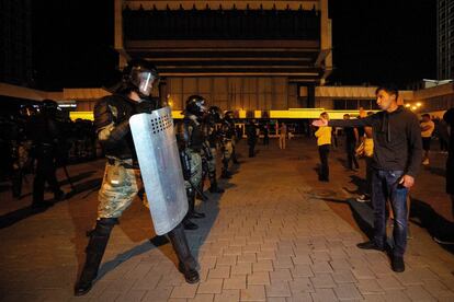 Un joven manifestante gesticula frente a un agente antidisturbios.