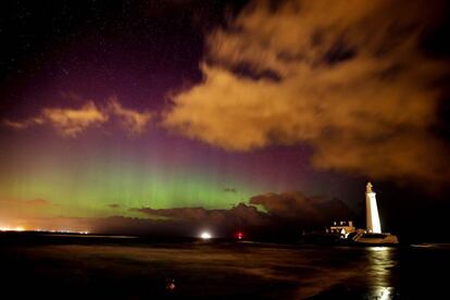 Les llums del nord brillen sobre el far de Santa Maria a Northumberland, Anglaterra.