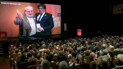 En la pantalla, Carles Puigdemont (derecha) y el 'exconseller' Lluís Puig, en una videoconferencia durante un mitin de Junts per Catalunya en Terrassa (Barcelona) en enero de 2023.