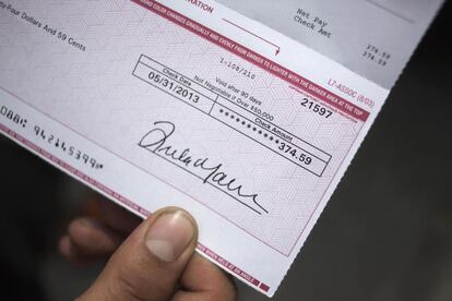 Javier Alava, de 27 años, muestra un cheque con su salario de 50 horas de trabajo en una tienda de repuestos de coches de Long Island, Nueva York (EE UU). Gana justo un poco más que el salario mínimo, y no va más allá de ocho euros por hora.
