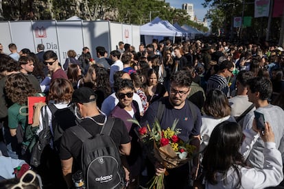 Centenares de personas, algunas de ellas con rosas pasean por el Paseo de Gracia, en Barcelona.