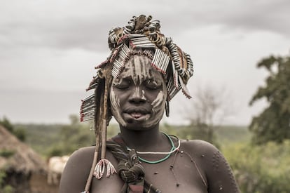 Una joven madre mursi posa con los ojos cerrados en el poblado de Marreke, en el Parque Nacional de Mago, con el arreo de una res a modo de tocado. Las escarificaciones que presenta en el brazo izquierdo, y que para los mursis suponen, como la perforación del labio, un distintivo de elevada belleza, están siendo suprimidas por el Gobierno etíope, como el cosido del labio inferior, conforme se aprecia en la imagen.