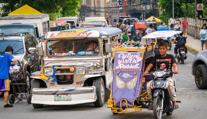 Uno de los populares 'yipnis' (autobuses) que circulan por Manila atestados de gente, junto a un 'rickshaw' (bicitaxi).