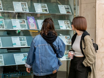 Dos personas observan la oferta de pisos en alquiler de una oficina inmobiliaria de Barcelona.