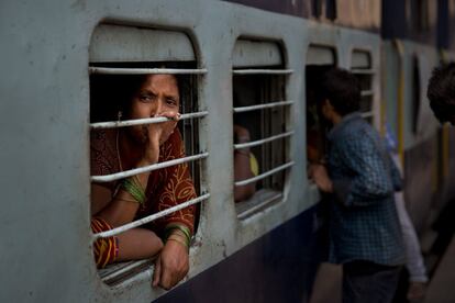 Una mujer se asoma a la ventanilla de un vagón de tren en la estación de Nueva Delhi, India.