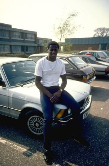 Justin Fashanu fotografiado sentado sobre el capó de su coche en 1981.