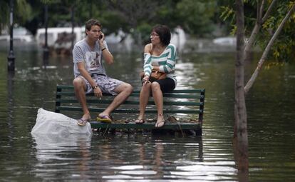 Una pareja espera en un banco a ser rescatados tras las lluvias caídas en Buenos Aires (Argentina).