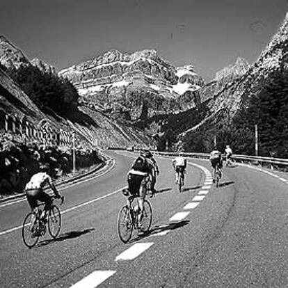 Aficionados al cicloturismo circulan por una carretera provistos de cascos.