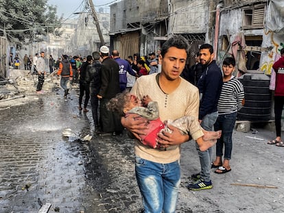 Un joven lleva en brazos a una niña víctima de un bombardeo en Rafah, en el sur de la franja de Gaza, el 1 de diciembre.