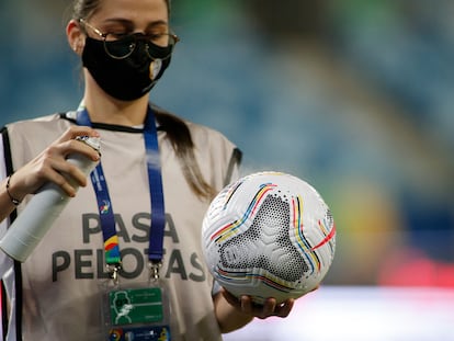 Una trabajadora de la Conmebol desinfecta un balón durante un partido entre Chile y Bolivia, en Cuiabá, en la Copa América.