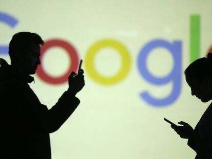 Dos personas navegan por el móvil con el logo de Google detrás. 