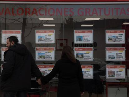 Dos jóvenes frente al escaparate de una inmobiliaria en el Ensanche de Vallecas, Madrid