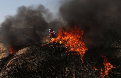 Un manifestante palestino huye del fuego y las llamas durante los enfrentamientos con Israel en la frontera de Gaza.