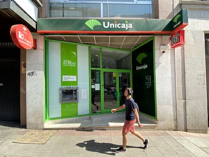 Una persona pasa por delante de una oficina de Unicaja.