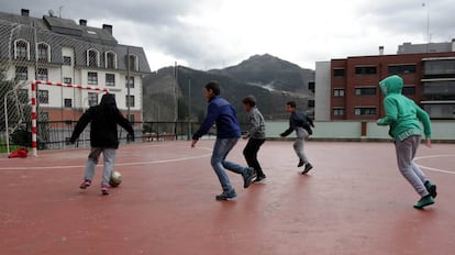 Varios niños juegan al futbol ajenos al humo del vertedero que tienen al fondo.