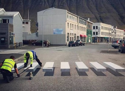 Dos operarios pintan el paso de cebra tridimensional en Ísafjörður (Islandia).