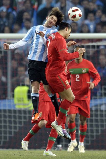 Messi y Cristiano disputan de cabeza un balón.