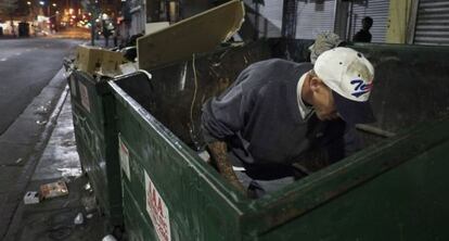 Un vagabundo busca comida en un contenedor de basura en Los Ángeles