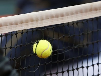 Una pelota se queda encajada en la red durante un partido de tenis.