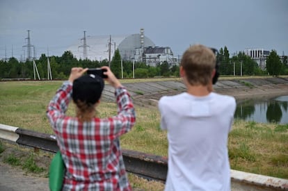 Dos turistas toman fotografías de la planta nuclear de Chernóbil y del sarcófago que cubre el reactor número 4, donde tuvo lugar el accidente en 1986. Algunos visitantes han sido criticados por no respetar la trágica historia del lugar con 'selfies' inapropiados, un tema cada vez más común en las zonas de desastre.