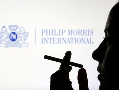 Una mujer fuma delante del logo de Philip Morris