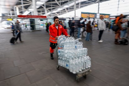 Un voluntario de Cruz Roja lleva agua en la estación Joaquín Sorolla de Valencia, este martes.