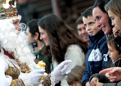 Una mujer mira sonríe al rey Melchor mientras éste saluda a los numerosos niños durante una cabalgata en Valencia.