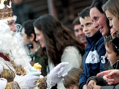 Una mujer mira sonríe al rey Melchor mientras éste saluda a los numerosos niños durante una cabalgata en Valencia.