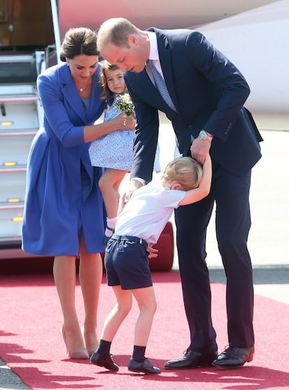 Los duques de Cambridge colocan a sus hijos para la foto ante los medios de comunicación congregados en el aeropuerto de Berlín. Kate Middleton lleva en brazos a la princesa Carlota y Guillermo de Inglaterra intenta convercer al príncipe Jorge para que se sitúe correctamente.