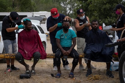 Migrantes haitianos reciben un corte de pelo gratuito en el parque donde se están albergando en Ciudad Acuña (México), este martes.