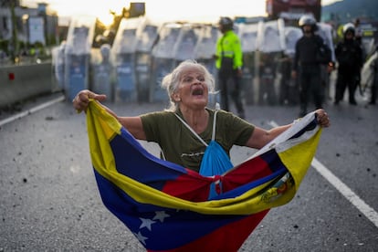 Una manifestante sostiene una bandera venezolana frente a la policía durante una propuesta por los resultados oficiales de las elecciones en Caracas (Venezuela), el 29 de julio de 2024.