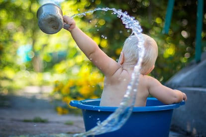 Un bebé juega con el agua en un barreño.