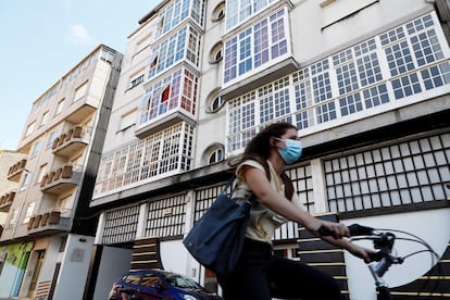 Una mujer monta en bicicleta junto al edificio 41 de la calle Duquesa de Alba, en la localidad lucense de Monforte de Lemos, que ha sido confinado por el Servizo Galego de Saúde.