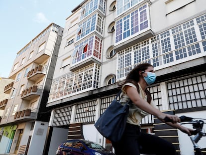 Una mujer monta en bicicleta junto al edificio 41 de la calle Duquesa de Alba, en la localidad lucense de Monforte de Lemos, que ha sido confinado por el Servizo Galego de Saúde.