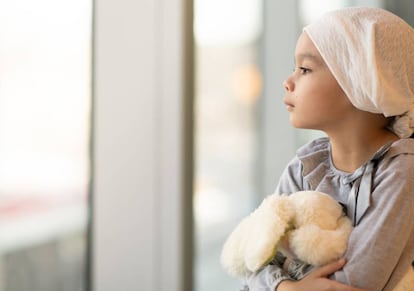 Niña con leucemia mira por la ventana.