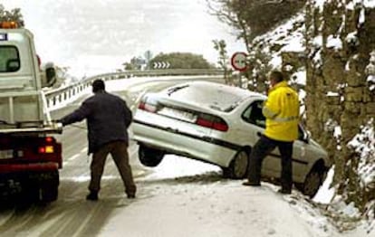 Una grúa retira un vehículo que se salió de la carretera por culpa de la nieve en el Coll d&#39;Ares en Castellón.