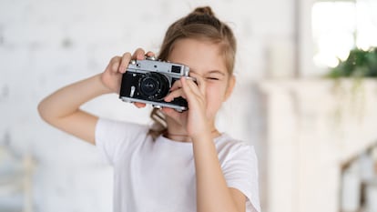 Una niña con una cámara vintage haciendo fotos.