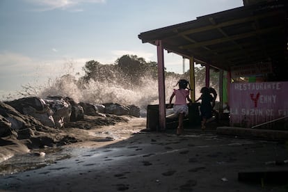 Niños juegan al lado de la barrera de costales.